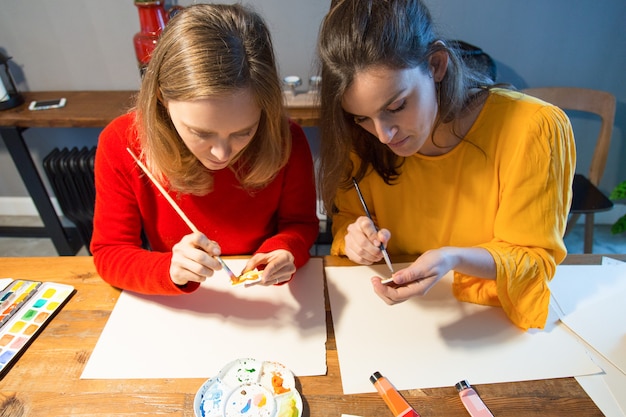 Two serious artist working with paintbrush and palette