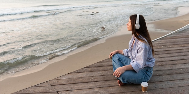 Side view woman sitting next to the beach with copy space
